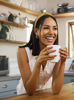Woman smiling while drinking coffee in kitchen